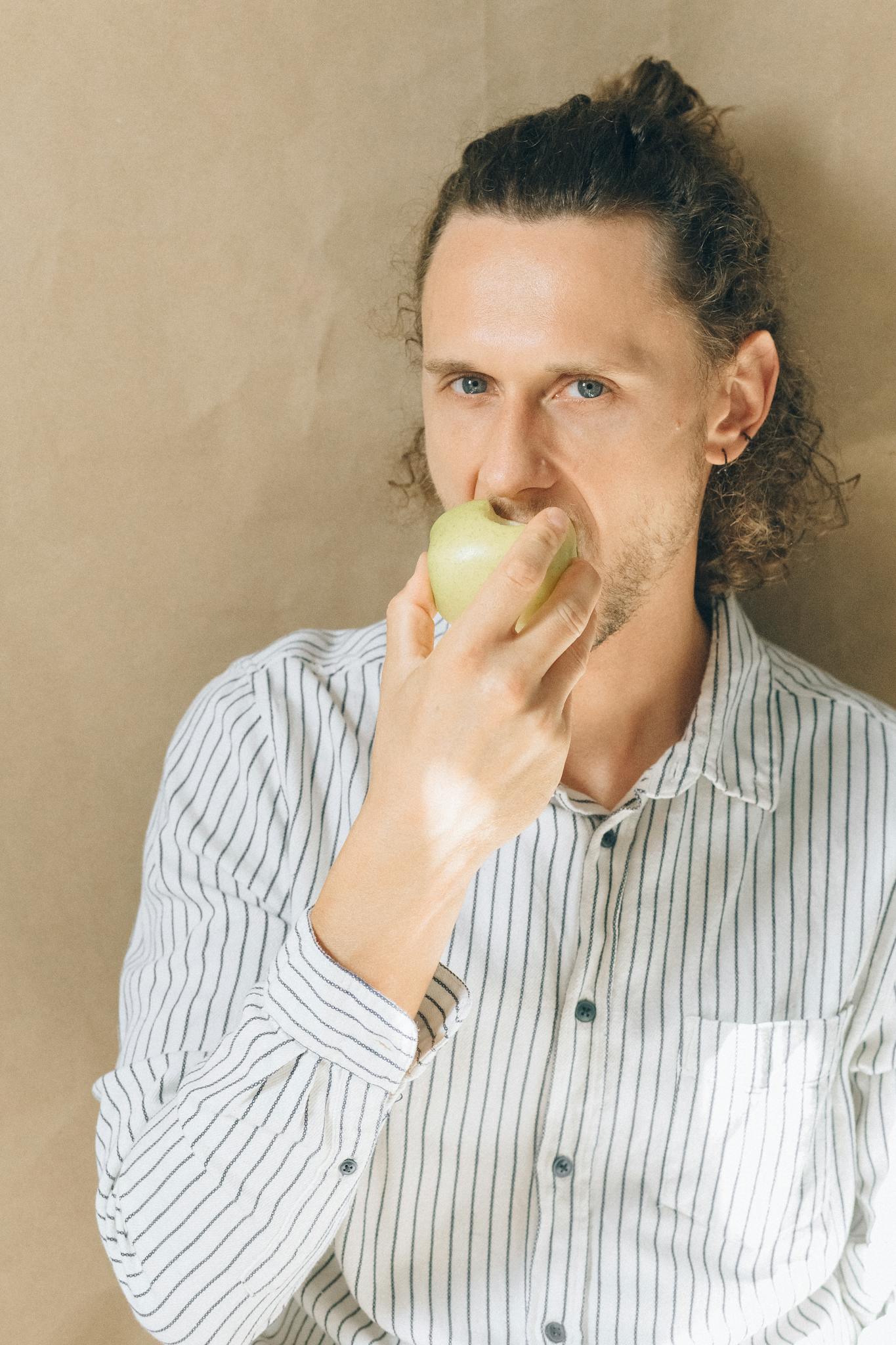 Portrait of a man enjoying a healthy green apple indoors, promoting wellness and lifestyle.